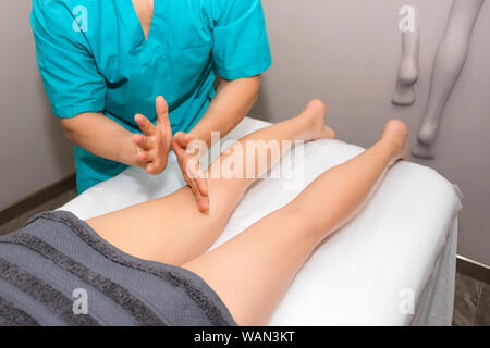 Terapeuta Profesional de masaje relajante en piernas dando tratamiento a una mujer en el balneario. Procedimientos de spa relajantes, masaje de cuerpo entero. Placer, descanso, cuidado del cuerpo Foto de stock