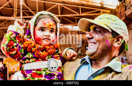 Barsana, India - Febrero 23, 2018 - El hombre muestra con orgullo su joven hija durante el festival de Holi Foto de stock