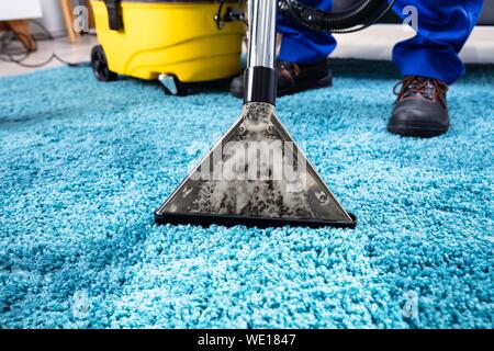 La persona utilizando una aspiradora para limpiar la alfombra azul en casa  Fotografía de stock - Alamy