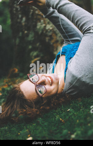 Retrato de una adolescente anteojos mientras está acostado sobre el césped