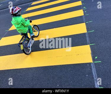 Un alto ángulo de visualización de Boy montando bicicleta en paso de cebra