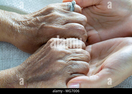 Una niña sostiene las manos de una anciana Closeup Foto de stock