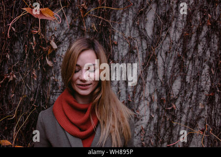 Retrato de mujer sonriente con los ojos cerrados en otoño