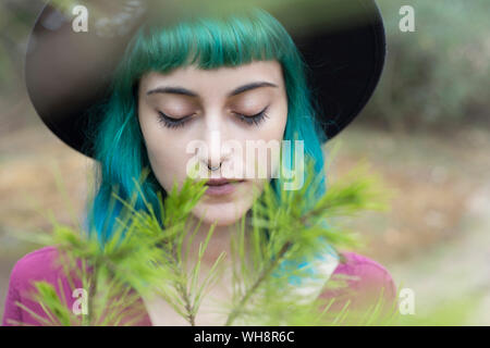 Retrato de mujer joven con el pelo teñido de azul y verde y nariz penetrante en la naturaleza Foto de stock