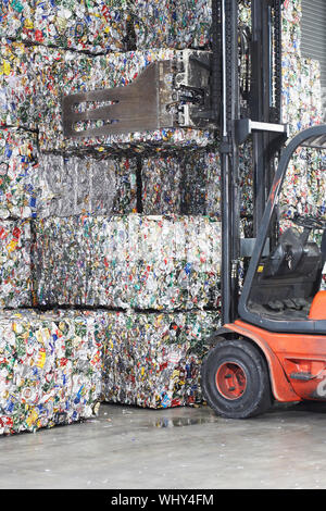 Carretilla elevadora cargando las pilas de productos reciclados en la planta de reciclado Foto de stock