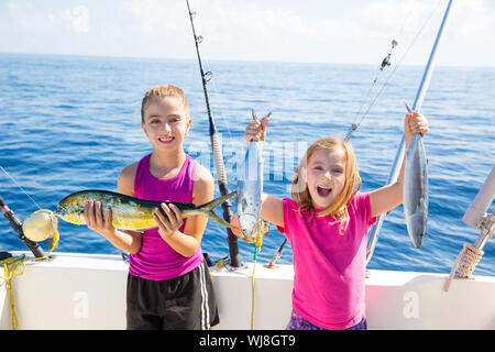 Feliz atún pescadoras kid chicas en barco con peces trolling con catch Mahi dorado Foto de stock