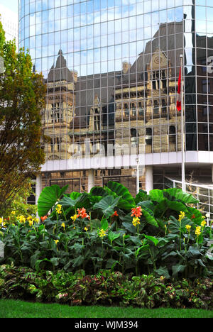 Reflejo del antiguo edificio del ayuntamiento de Toronto en una pared de vidrio de un moderno y alto.