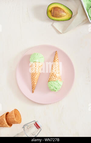 Helado de aguacate verde recoge en conos wafle sobre fondo blanco. Espacio de copia Foto de stock