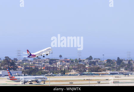 Los Angeles, California, USA - Mayo 22, 2019: Un Hawaiian Airlines avión despega desde el Aeropuerto Internacional de Los Ángeles (LAX). En primer plano un am Foto de stock