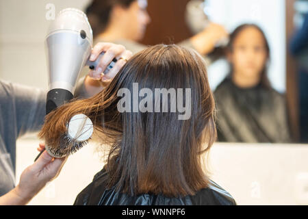 Madre cortando el cabello a su hija en casa Foto de stock