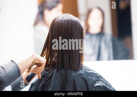 Madre cortando el cabello a su hija en casa Foto de stock