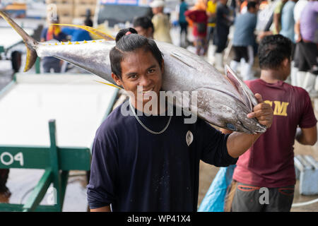 Un hombre llevando un gran Rabil sobre su hombro,dentro del Fishport en General Santos, Filipinas Foto de stock