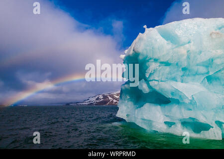 Estiramiento del arco iris a un iceberg verde en el Océano Artico, Hornsund Svalbard Noruega.