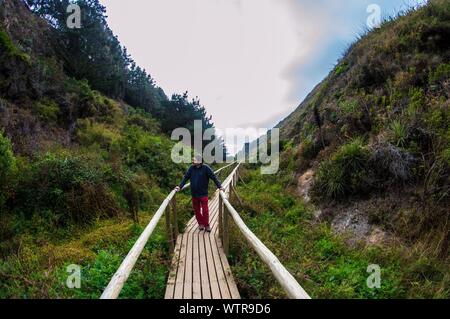 Hombre caminando sobre la Pasarela en medio de las montañas contra el cielo