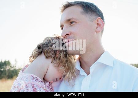 Retrato de padre llevar a su hija fuera al atardecer