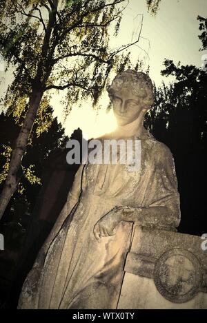 Ángulo de visión baja de escultura femenina en el cementerio contra el cielo