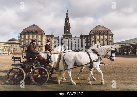 20 de febrero de 2019. Oficial militar entrenando dos caballos blancos de los establos reales en frente. Caballos y carrito con jinete en el palacio de Christianborg. Real