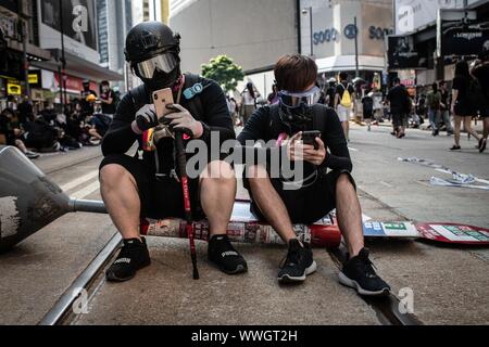 Hong Kong. 15 Sep, 2019. Los manifestantes sentarse en la calle mientras toman parte durante una marcha en pro de la democracia. Los manifestantes continúan demostrando a través de Hong Kong para la decimoquinta semana consecutiva. Después de marchar durante unas horas de la Bahía Causeway hacia el Admiralty, enfrentamientos entre los manifestantes y la policía antidisturbios ocurrió en diferentes partes de la isla. Crédito: Sopa de imágenes limitado/Alamy Live News