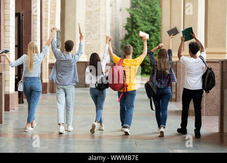 Hemos aprobado los exámenes. Estudiantes levantó las manos y caminar en el campus Foto de stock