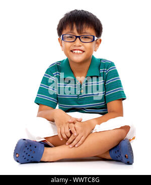 Cheeky Boy piernas cruzadas sentados en el suelo y sonriendo Foto de stock