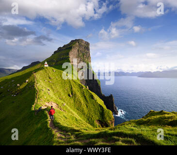 Kallur faro en la isla Kalsoy. Senderismo en las islas Feroe. El Turista en una chaqueta roja visitar una atracción turística. Paisaje de montaña de verano