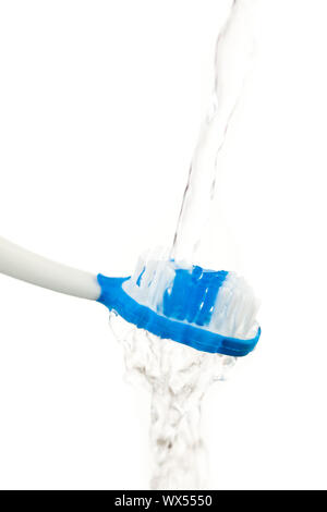 El agua que fluye en un cepillo de dientes contra el fondo blanco. Foto de stock