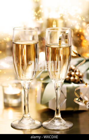 Copas de champagne brillante con velas y regalos Foto de stock