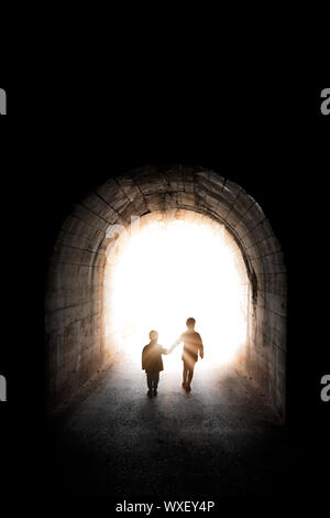 Dos pequeños hermanos caminando hacia la luz Foto de stock
