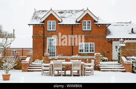Casa patrimonial y jardines cubiertos de nieve en invierno, Inglaterra, Reino Unido. Foto de stock