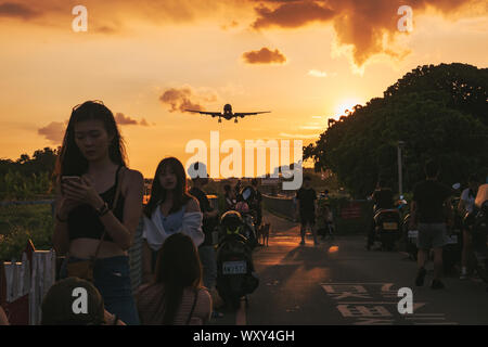 Los espectadores se preparan para una foto de un Airbus A330 enfoques al atardecer a aterrizar en el aeropuerto Songshan de Taipei, Taiwán