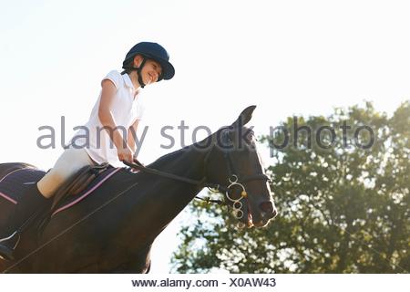 Ángulo de visión baja de chica en caballo en campo