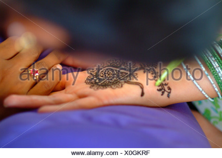 La mujer que recibe un tinte de henna mendhi ( ) diseño en su mano antes de su boda india