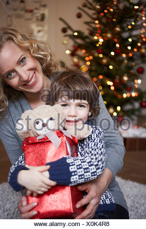 Mamá sobre suelo sujetando hijita y acariciar a Pug familia Fotografía