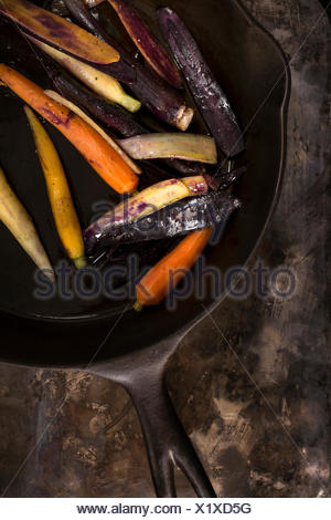 Sartén rainbow las zanahorias en un sartén de hierro fundido sobre una superficie metálica de estilo rústico.