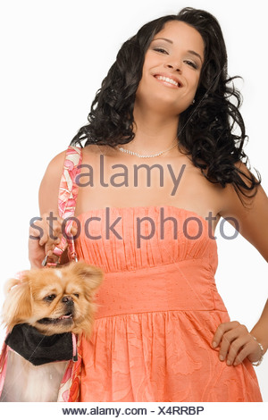 Retrato de una joven mujer que llevaba un perro Pomerania en una bolsa y sonriente