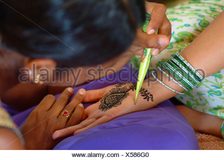 La mujer que recibe un tinte de henna mendhi ( ) diseño en su mano antes de su boda india