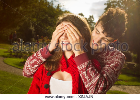 El hombre que cubren los ojos de la novia en el parque