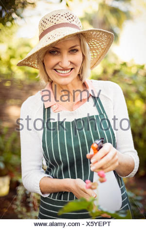Mujer sonriente mientras que regar las plantas