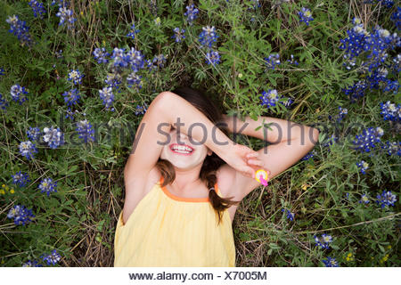 Una niña acostada sobre su espalda con su brazo por encima de los ojos.