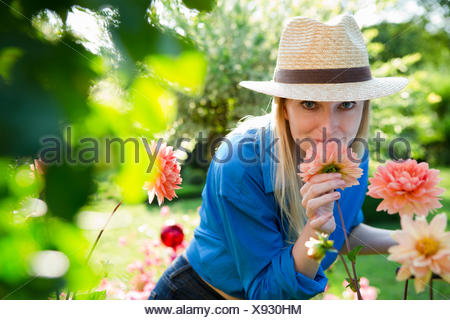 Retrato de mujer adulta media oliendo flores de jardín