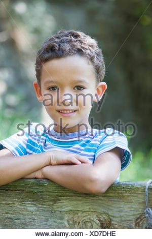 Retrato de niño recostado sobre la valla del jardín