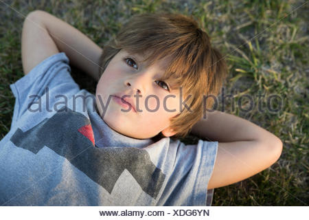 Retrato de niño acostado sobre la hierba del parque mirando hacia arriba