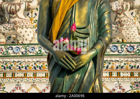 Sculpture Bouddha Debout enveloppée de robe dorée, avec des fleurs de lotus kasaya, placé dans ses mains. Wat Arun, Temple de l'aube, Bangkok, Thaïlande. Statue Banque D'Images