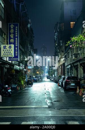 Kaohsiung, Taiwan : une sombre ruelle urbaine, à une nuit pluvieuse avec la Tuntex Sky Tower 85 au bout de la rue. Sur le tarmac mouillé reflétant les lumières Banque D'Images