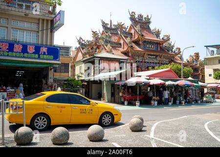 Kaohsiung, Taiwan : Yellow Taxi voiture en face d'un ancien temple chinois taosim (CIH Ji Palace) dans l'architecture traditionnelle chinoise avec petit marché Banque D'Images