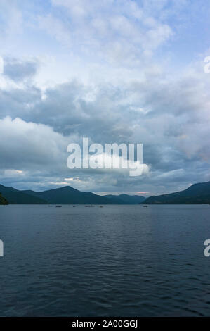 Crépuscule sur le lac de montagne avec des bateaux de pêche dans la distance. Le lac Ashi, Hakone, Japon Banque D'Images