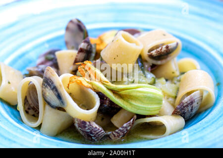 Plat de pâtes avec les coquillages et fleurs de courgettes, appelé calamarata, recette traditionnelle de la cuisine de Naples, Italie Banque D'Images