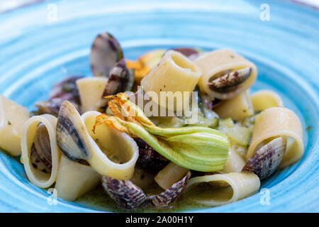 Plat de pâtes avec les coquillages et fleurs de courgettes, appelé calamarata, recette traditionnelle de la cuisine de Naples, Italie Banque D'Images