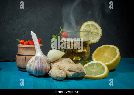 La vie toujours avec des ingrédients pour la santé de l'infusion avec de la racine fraîche de gingembre, citron, ail et cynorrhodons avec un verre de tisane sur une Banque D'Images