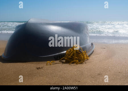 Bateau chaviré sur la plage de sable. Du beau temps et de petites vagues Banque D'Images